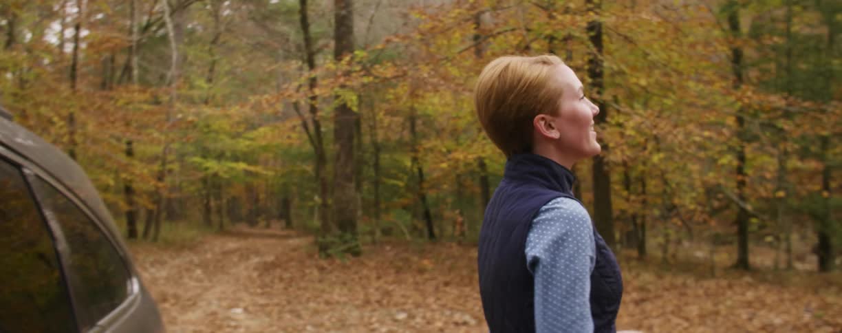 Woman smiling and looking at the forest on a fall day
