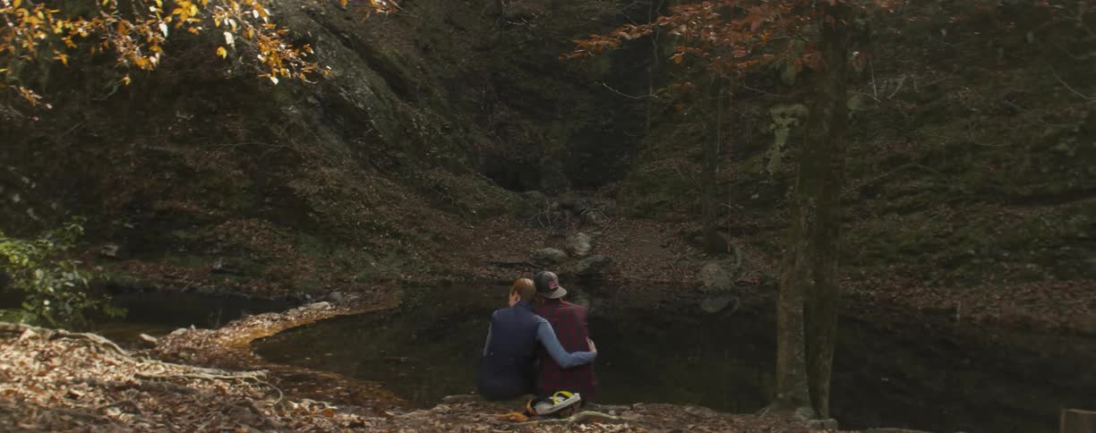 Two people hug near a pond