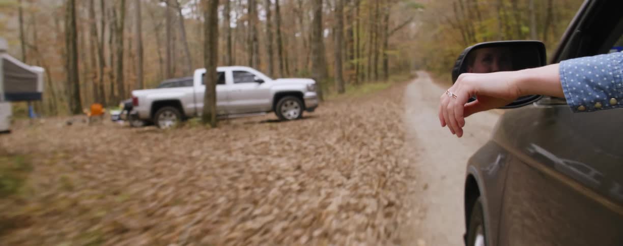 A car is racing down a small road by the forest