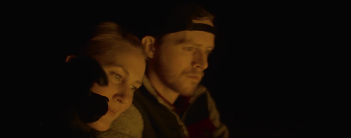 Man and woman's faces illuminated by firelight