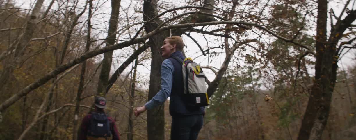 A couple of men standing in the woods looking around and talking
