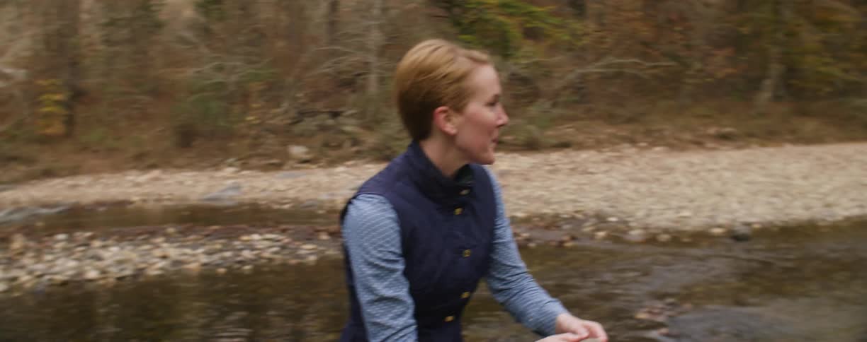 A woman skips a stone on the stream