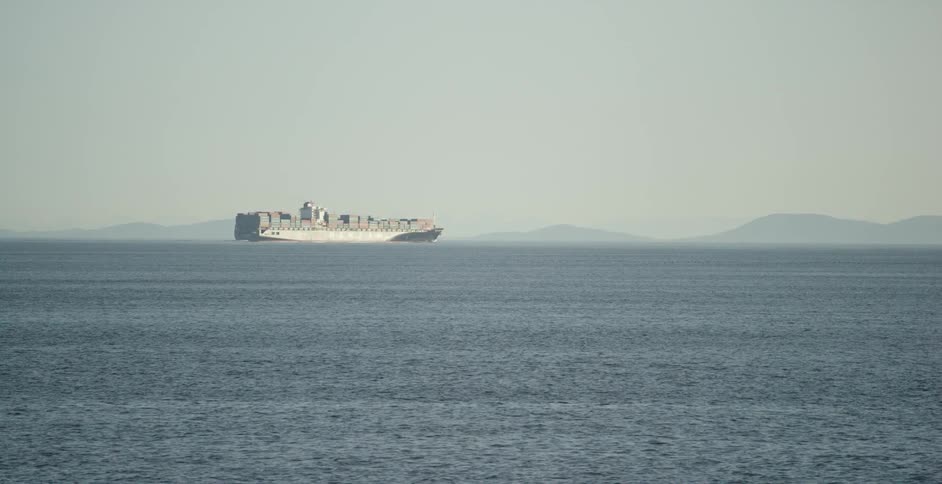 A ship at sea with mountains in the background