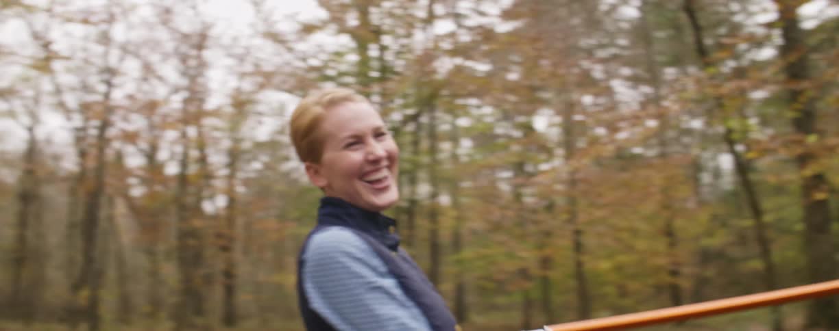 Three friends laugh while setting up a tent outdoors