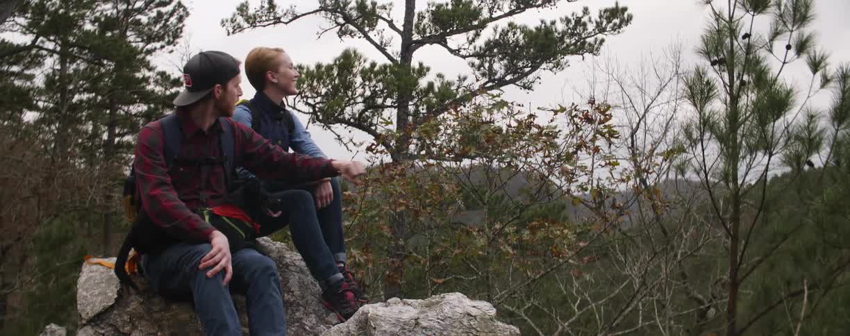 Man and woman sitting on a rock in the woods