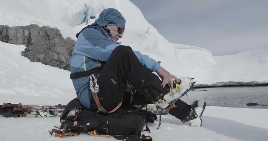 Man secures crampons to his boots in preparation to walk on ice