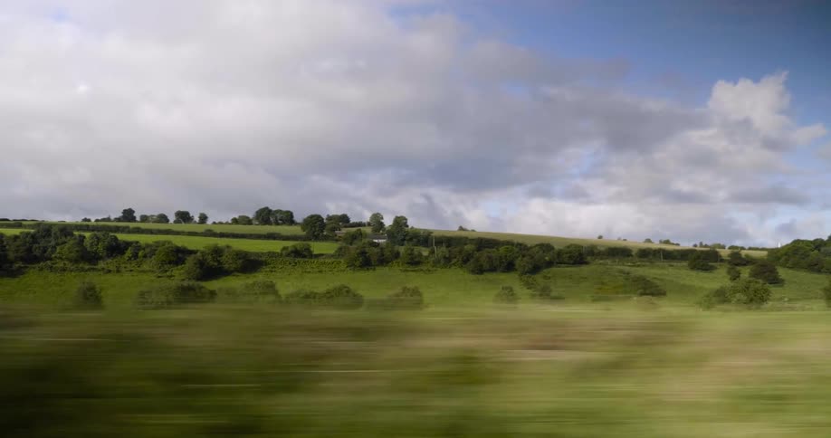 A vehicle drives in a rural area on a cloudy day