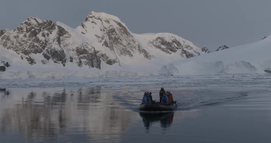A boat carries people on a still mountain lake in winter
