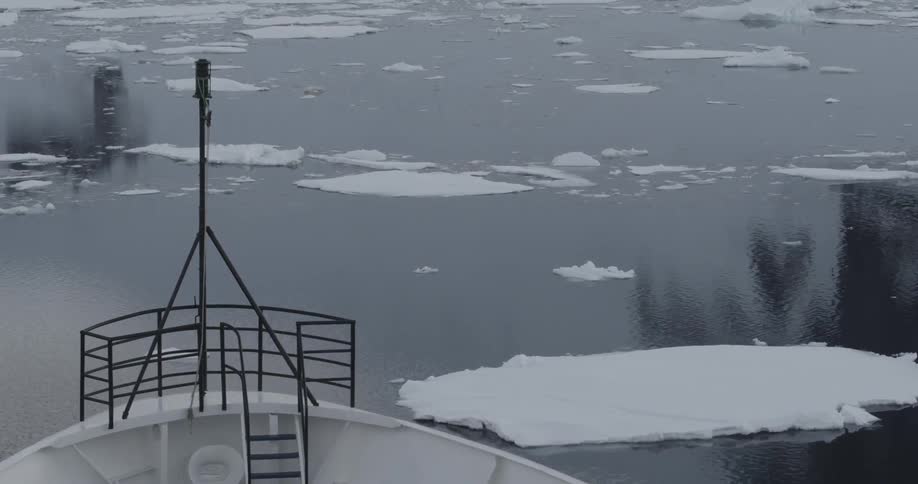A ship's bow is making its way over an icy sea during the day