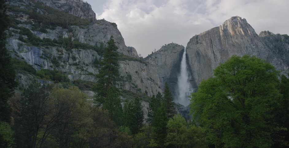 A waterfall over a sheer cliff with trees at the base