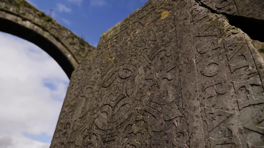 A stone arch is near a slab with etchings in it