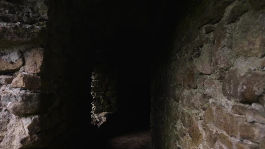 Shadow obscures the pathway between two old stone walls