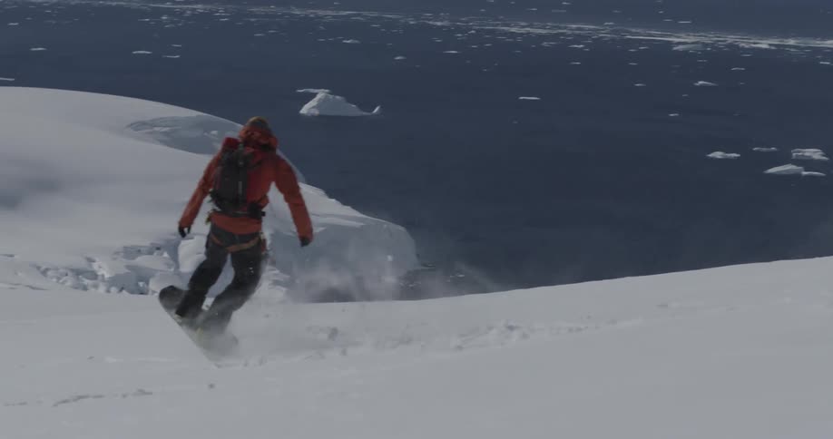A man snowboards down a slope near the sea
