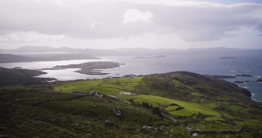 Green hills littered with rocks leading to a body of water