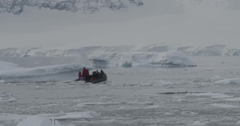 An inflatable boat filled with people motors through icy waters