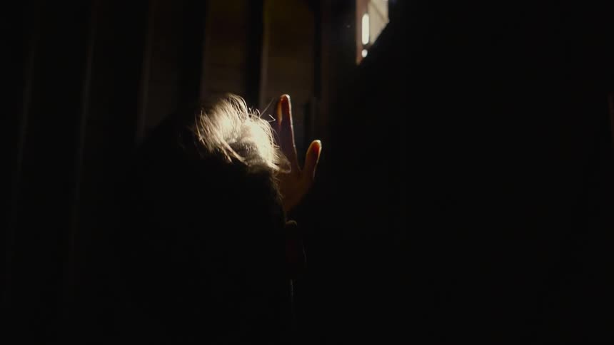 Sunlight shines through a window onto a man's face and hands