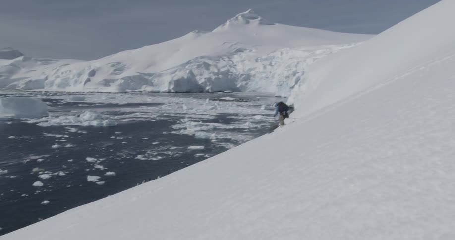 A man skiing down a mountain with water at the bottom on a sunny day