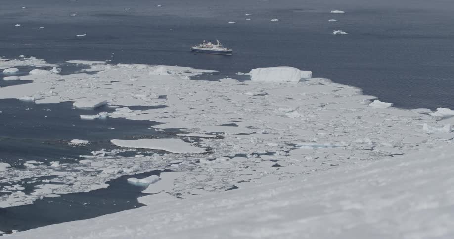 A ship is making its way through icebergs and sheet ice during the day