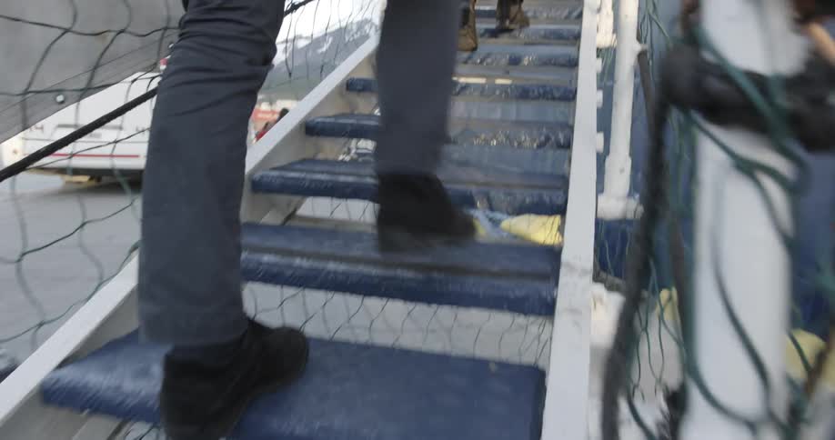 A man climbs up gangway steps to board a ship