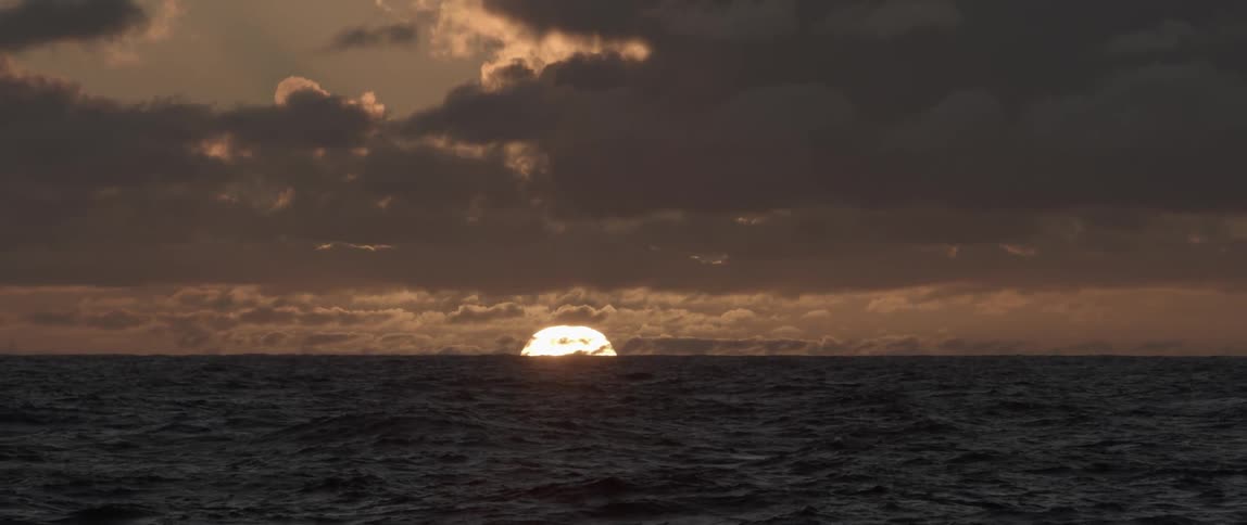 The sun going down over the horizon and ocean at dusk
