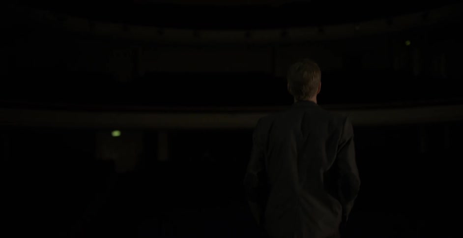 A man is walking around a dark auditorium
