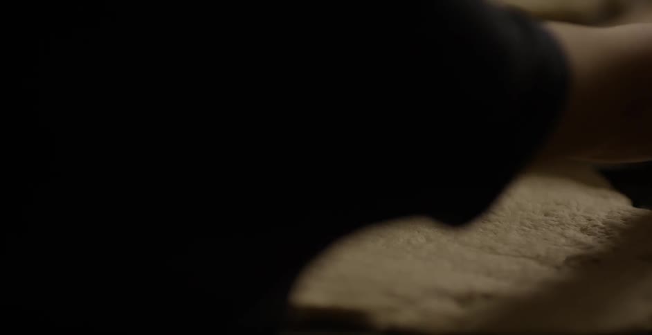 A person is flattening dough with a rolling pin