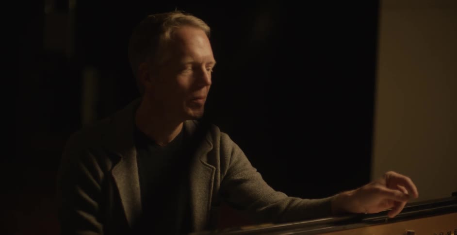 A man is sitting by a piano laughing