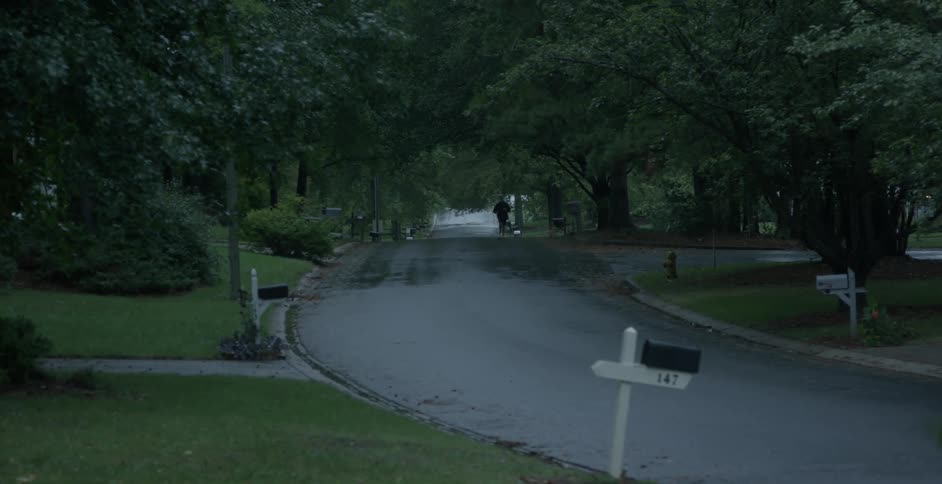 A man jogs down a road wet with rain