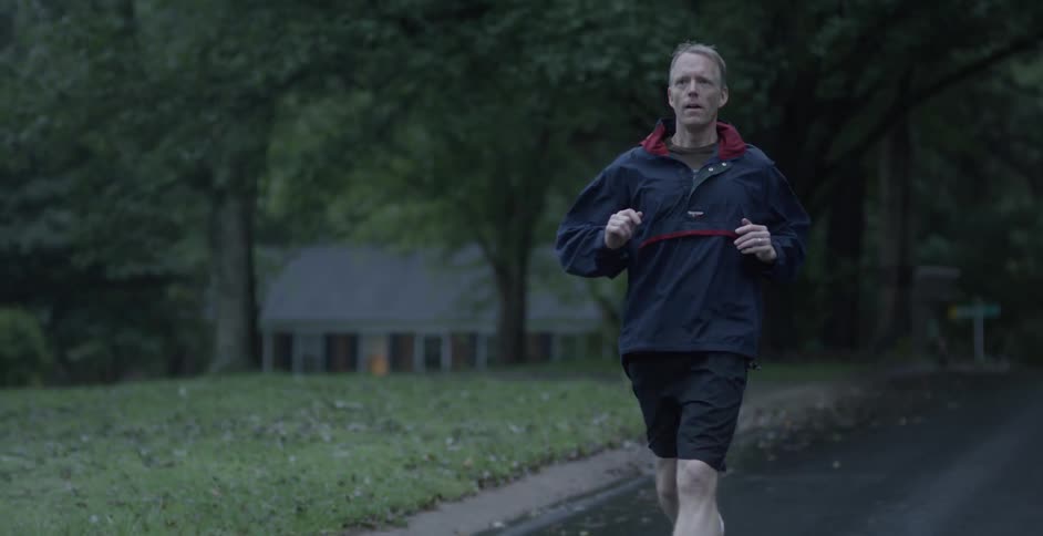 A man is running outside past the green lawns