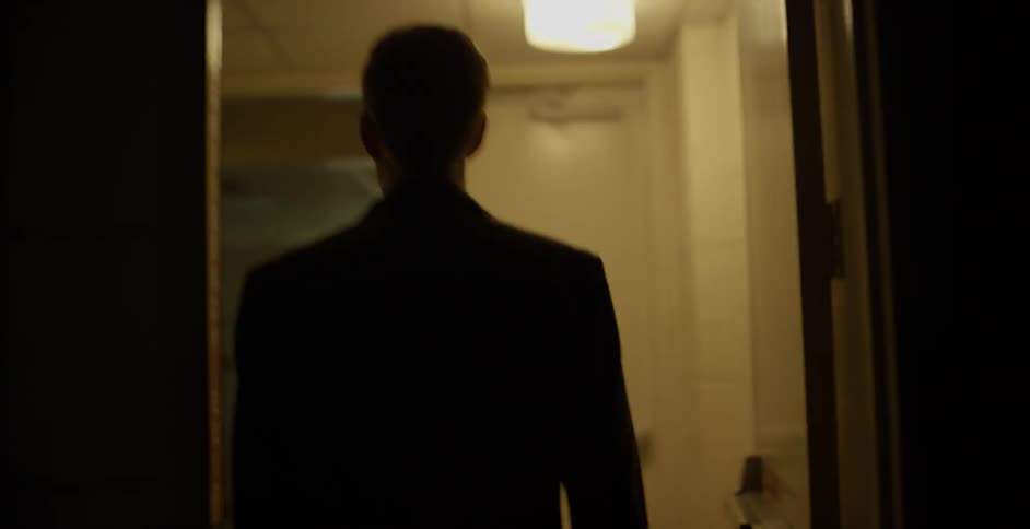 A man walks into a long dark hall