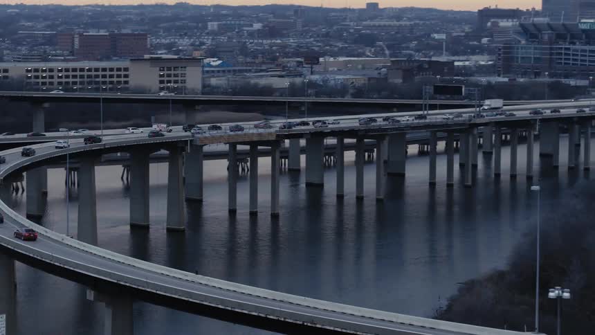 Vehicles driving on a highway over a river next to a city