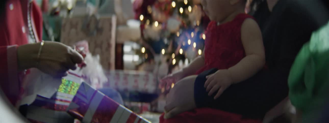 A woman unwraps a present for a baby at christmas