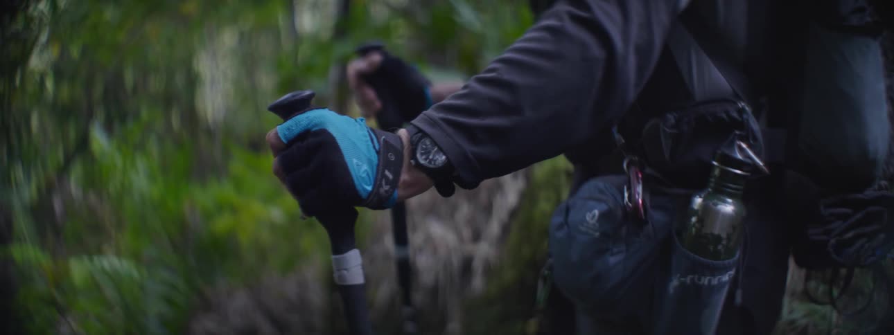 A man rests his hands on his hiking poles