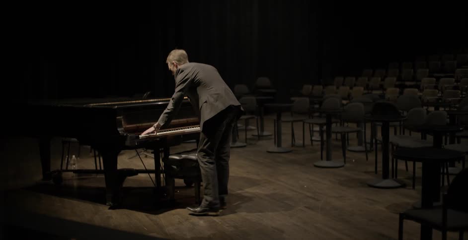 A man plays piano in an empty auditorium
