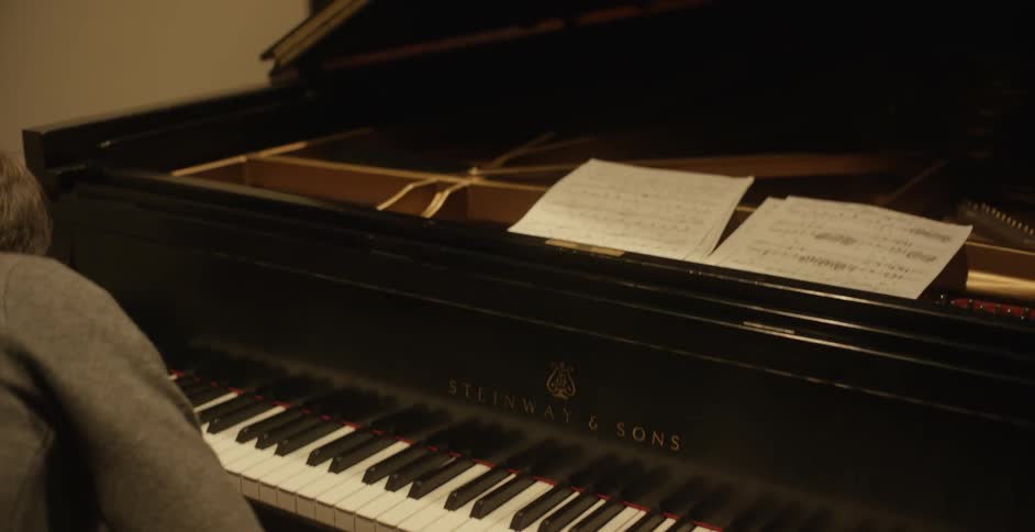 A man places sheet music on a piano