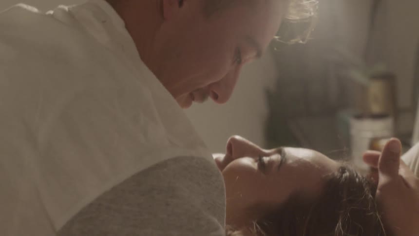 Man and woman lay in bed together kissing