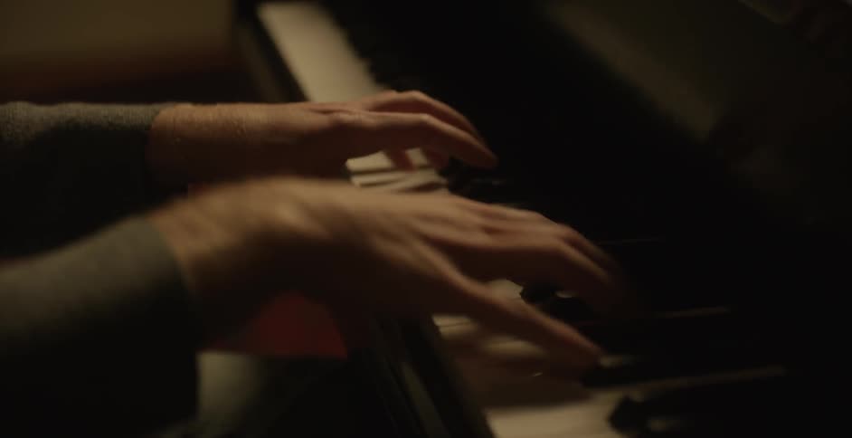Two hands play the keys on a piano