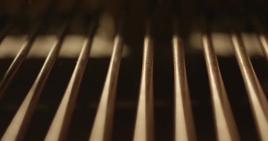 Piano strings vibrating and throwing up dust