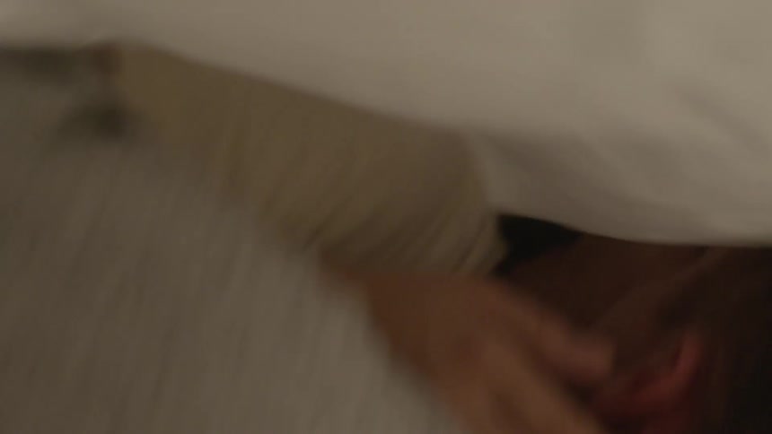 A man and woman kiss under the sheets