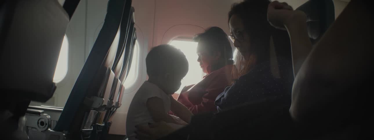 A woman on a plane holds her baby in her lap