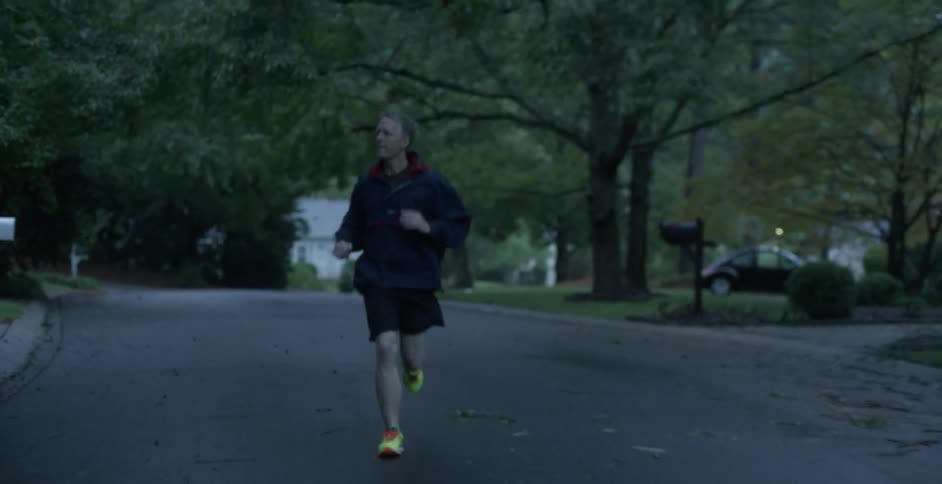 A man is running down the street past houses