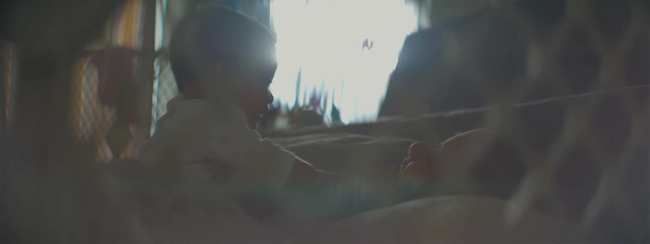 A baby plays with its mother in bed