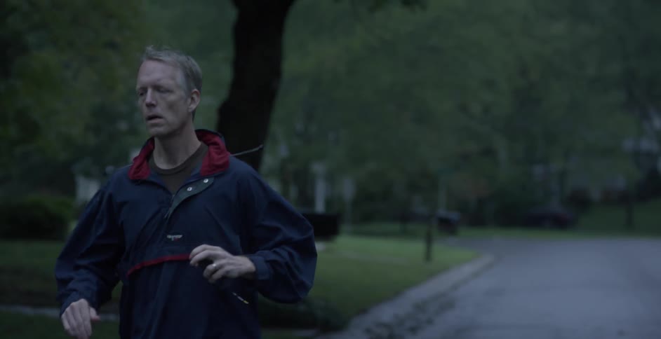A man jogs past houses on a neighborhood road