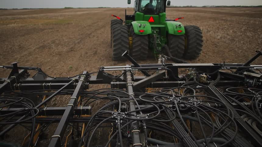 A tractor pulls farm equipment across a field