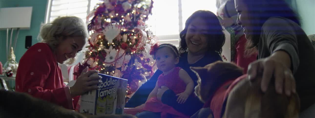 A family opens presents around the tree at christmas