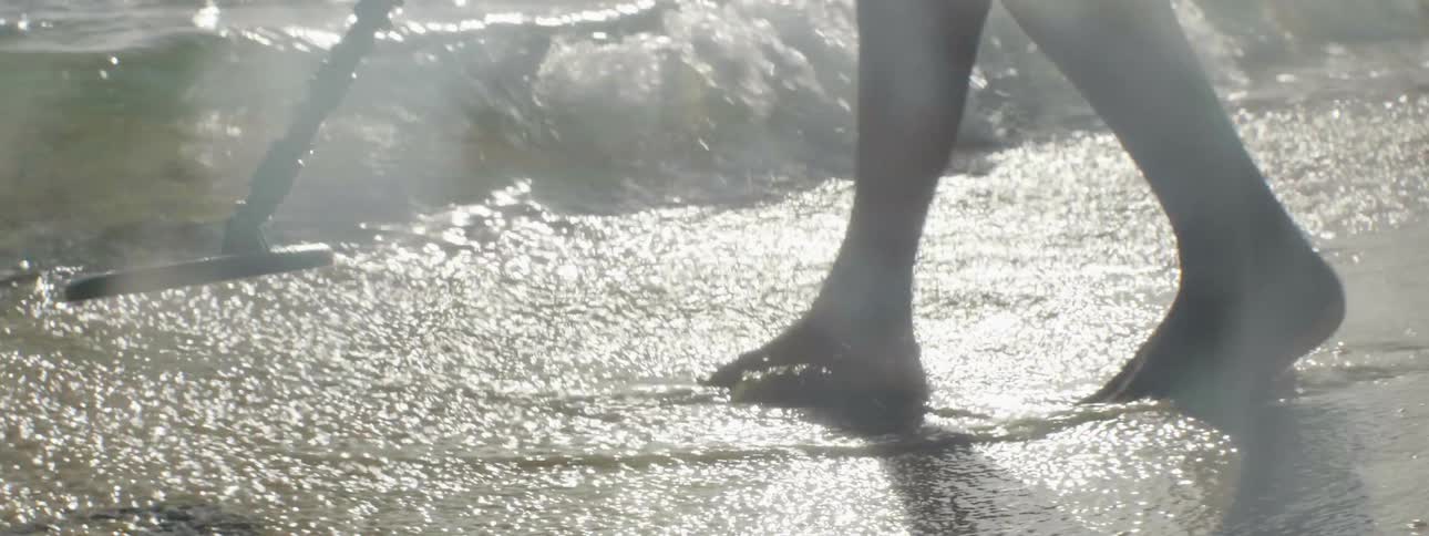 A man uses a metal detector on the beach