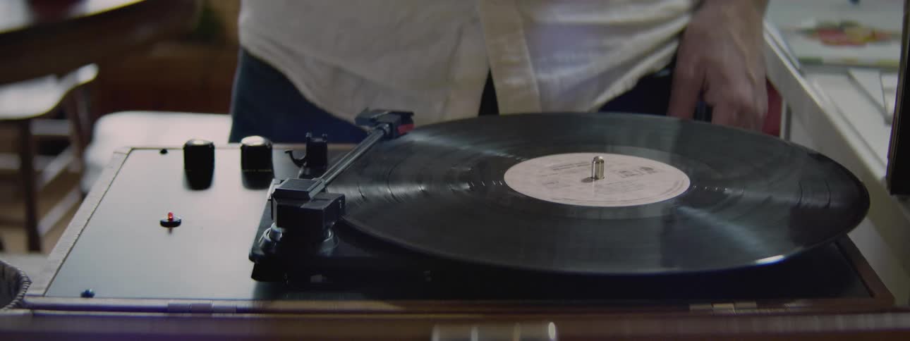 A man turns the knob starting his record player