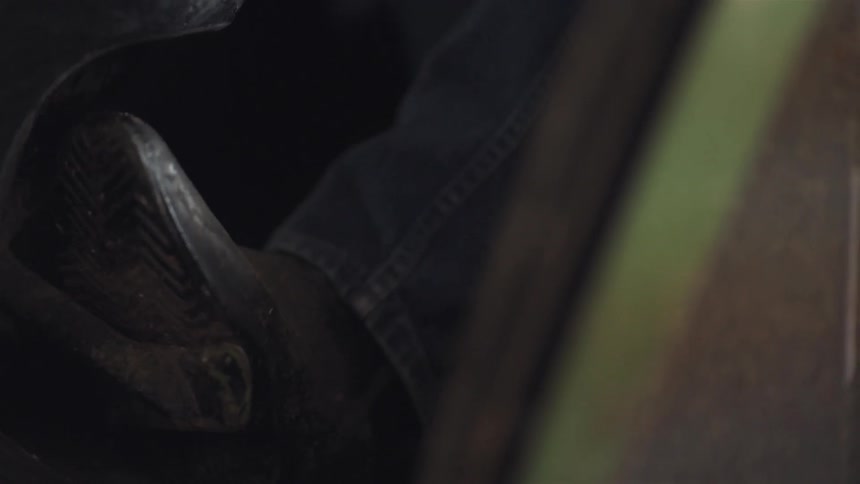 A person puts their booted foot on a lever