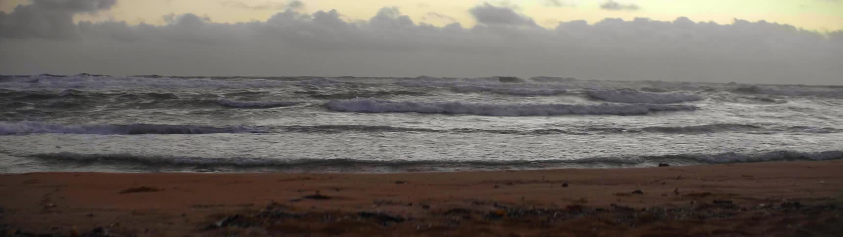 The waves slowly come on the shore at sunset