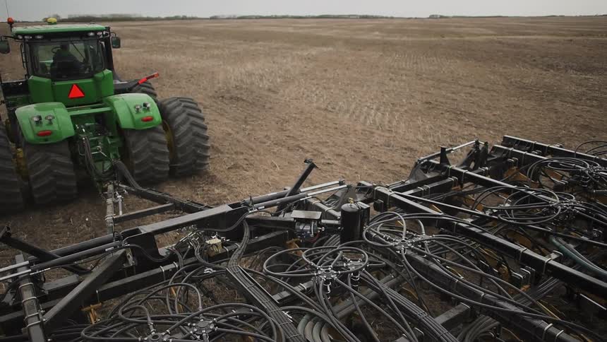 Tractor pulling a large piece of equipment in a field